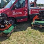 Der Deitmer Transporter und zwei Fällgreifer stehen auf einer Wiese.